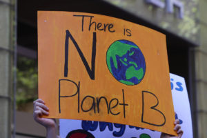 A protest banner reading "there is no planet B"