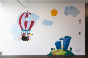Painted mural of hot air balloon and clouds and sun on wall