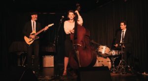 Mary Hart Trio: Three musicians playing jazz music, holding a cello, bass guitar and drums.